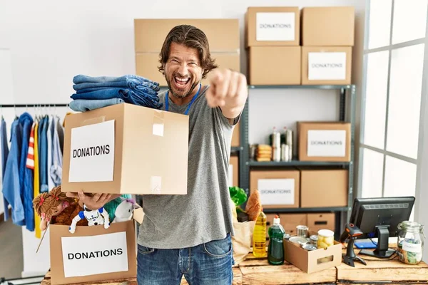 Gönüllü standı için bağış kutusu tutan yakışıklı orta yaşlı bir adam kameraya kızgın ve sinirli bir şekilde bakıyor. 