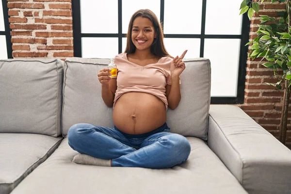 Mujer Embarazada Joven Sosteniendo Aceite Hidratante Para Hidratar Vientre Sonriendo — Foto de Stock