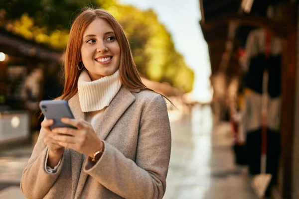 Νεαρή Κοκκινομάλλα Κορίτσι Χαμογελώντας Ευτυχισμένη Χρησιμοποιώντας Smartphone Στην Πόλη — Φωτογραφία Αρχείου