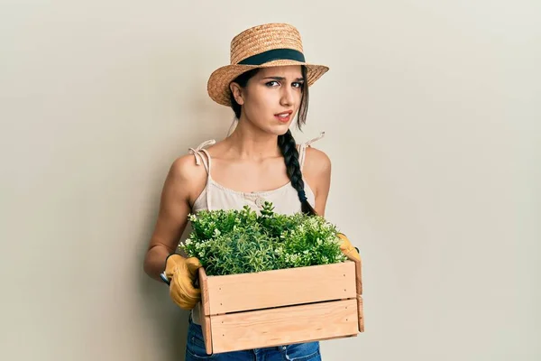 Young Hispanic Woman Holding Green Plant Pot Clueless Confused Expression — ストック写真