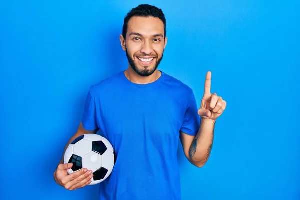 Латиноамериканець Бородою Тримає Футбольний Великою Посмішкою Обличчі Вказуючи Пальцем Збоку — стокове фото