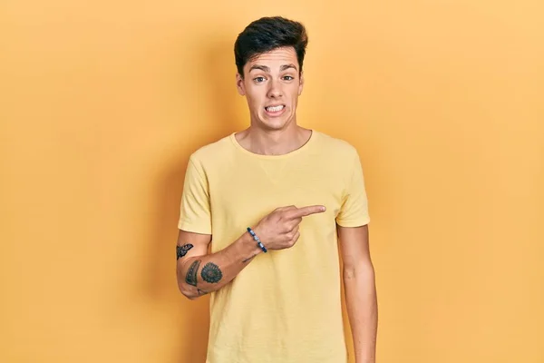 Young Hispanic Man Wearing Casual Yellow Shirt Pointing Aside Worried — Stock Photo, Image