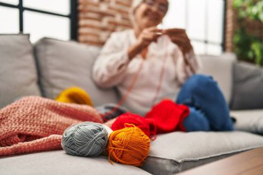 Orta yaşlı bir kadın evde kanepede oturuyor.