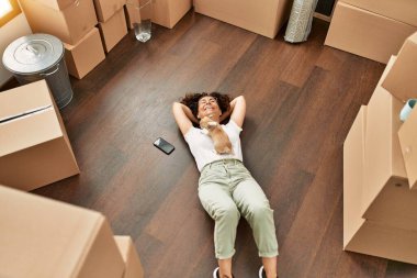 Orta yaşlı İspanyol kadın gülümsüyor. Yeni evinde kendine güvenen bir chihuahua tutuyor.