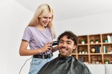 Genç bir kadın evdeki erkek arkadaşına saç kesiyor..