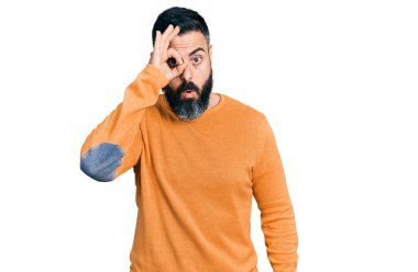 Sakallı, sıradan bir kazak giyen, şaşırmış yüzüyle şaşırmış, parmaklarından bakan İspanyol bir adam. İnançsız ifade. 