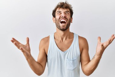 Soyutlanmış arka planda duran yakışıklı genç adam kızgın ve çılgın bir şekilde bağırıyor ve agresif bir ifade ve kollarla bağırıyor. Hayal kırıklığı konsepti. 