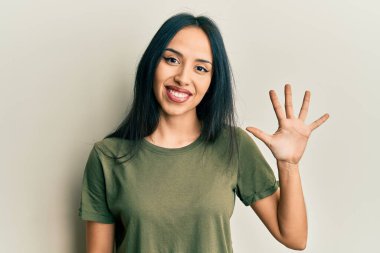 Gündelik tişört giyen genç İspanyol kız beş numarayı gösterip işaret ederken kendinden emin ve mutlu gülümsüyor.. 