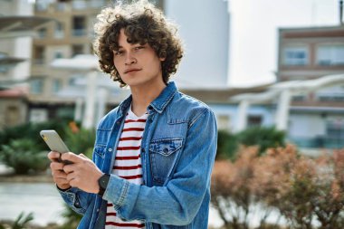 Genç İspanyol adam şehirde akıllı telefon kullanıyor.