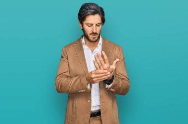 İş kıyafetleri giymiş genç İspanyol bir adam ellerinde ve parmaklarında ağrı, eklem iltihabı. 
