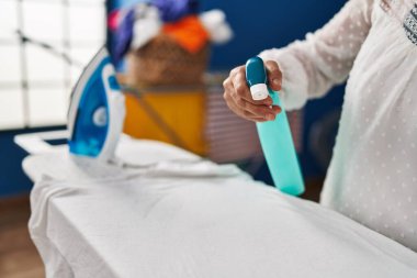 Çamaşırhanede ütü yapan orta yaşlı bir kadın.