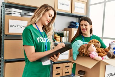 İki gönüllü kadın, hayır kurumunda çalışmaktan mutlu gülümsüyor..