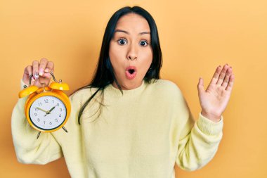 Burnuna piercing takan güzel İspanyol kadın. Alarm saatini tutuyor. Şaşırmak için ağzı açık kalmış, şaşırmış ve korkmuş. 