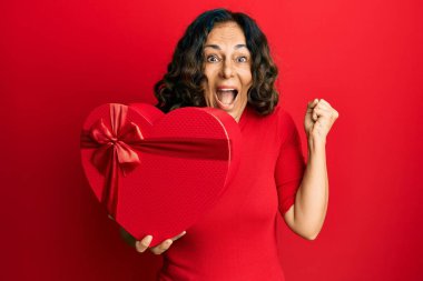 Orta yaşlı İspanyol kadın sevgililer günü hediyesi tutuyor. Gururla bağırıyor, zaferi ve başarıyı kutluyor. Kollarını kaldırıp heyecanla bekliyor. 