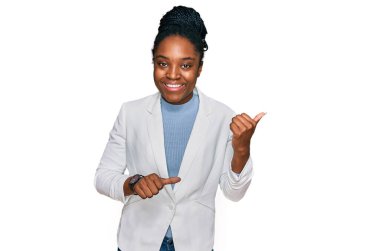 Genç Afro-Amerikan kadın, iş kıyafetleri giymiş. Arkayı işaret ediyor. Elleri havada, kendinden emin gülümsüyor. 