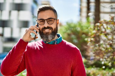 Genç İspanyol yönetici gülümsüyor. Şehirdeki akıllı telefondan konuşuyor..