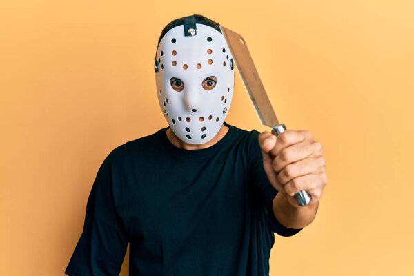 Man wearing hockey mask holding butcher knife looking dangerous and threatening