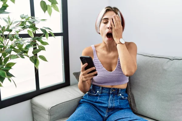 Young Beautiful Woman Using Smartphone Typing Message Sitting Sofa Yawning — Stock Photo, Image