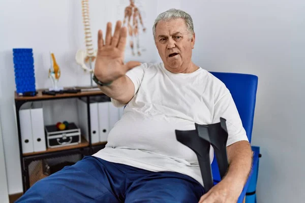 Hombre Caucásico Mayor Clínica Fisioterapia Sosteniendo Muletas Haciendo Gesto Stop — Foto de Stock