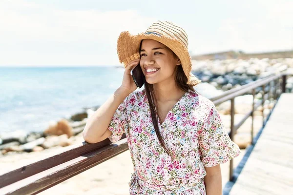 年轻的拉丁女孩戴着夏帽在海滩用智能手机聊天 — 图库照片