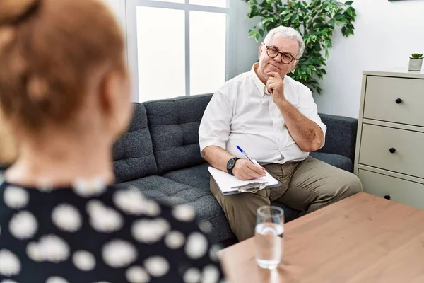 Muayenehanedeki kıdemli psikolog elleri çenesinde sorgulamayı, düşünceli ifadeyi düşünüyor. Gülümseyen ve düşünceli bir yüz. şüphe kavramı. 