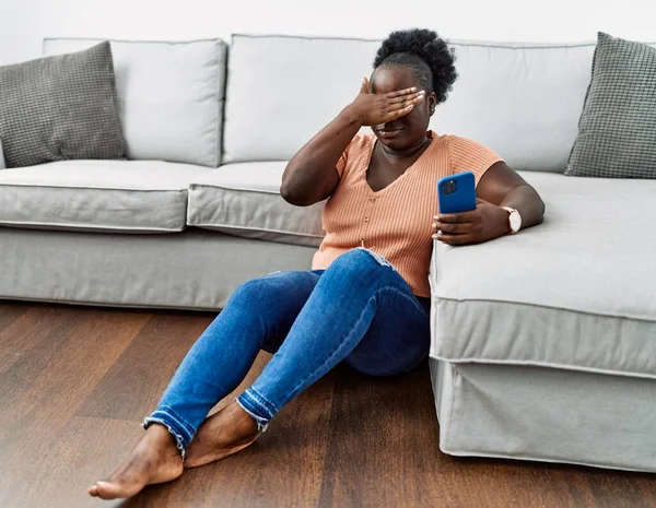 Young African Woman Using Smartphone Sitting Floor Home Covering Eyes — ストック写真