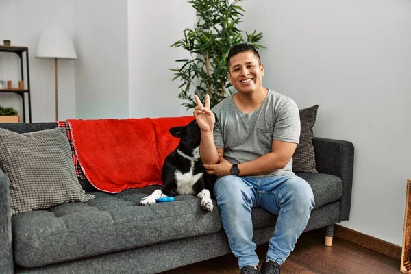 Jovem Latino Homem Cão Sentado Sofá Casa Sorrindo Com Rosto — Fotografia de Stock