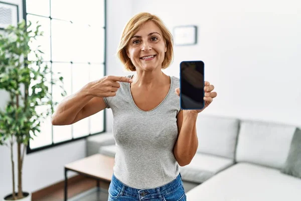 Mulher Loira Meia Idade Trabalhando Segurando Smartphone Mostrando Tela Sorrindo — Fotografia de Stock