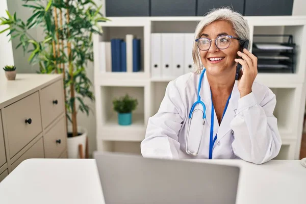 Mujer Mediana Edad Vistiendo Uniforme Médico Hablando Teléfono Inteligente Clínica —  Fotos de Stock