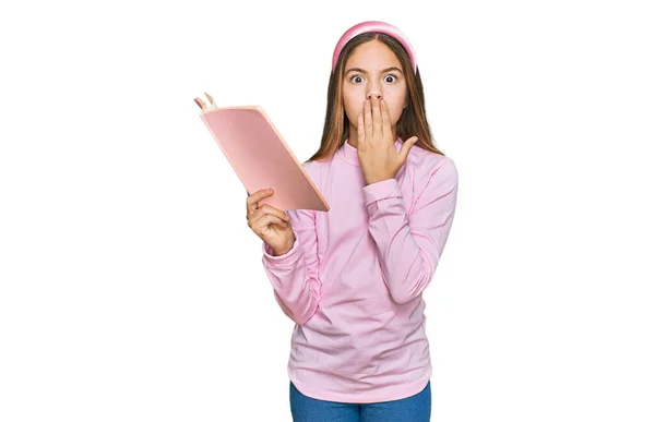 Beautiful Brunette Little Girl Reading Book Covering Mouth Hand Shocked — ストック写真