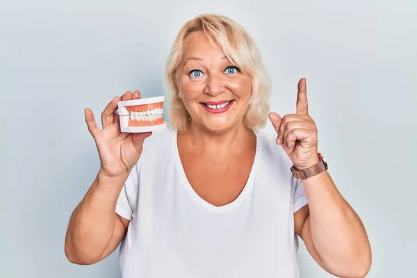 Middle Age Blonde Woman Holding Denture Surprised Idea Question Pointing — Stock Photo, Image