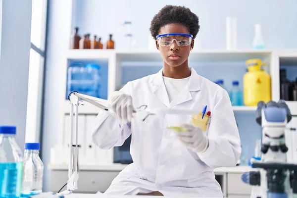 实验室使用放大镜穿着科学家制服的非洲裔美国妇女 — 图库照片