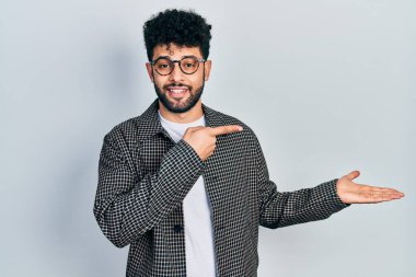 Sakallı genç Arap adam kameraya hayret ediyor ve gülümsüyor.. 