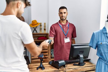 Genç İspanyol müşteri mağazada kredi kartıyla dükkan sahibine ödeme yapıyor..