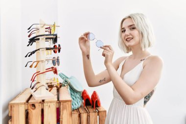 Giysi mağazasında kendine güvenen, gülümseyen beyaz bir kadın.