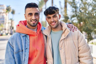 İki erkek caddede birbirlerine sarılıyorlar.