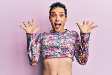 Makyaj elbisesi giymiş yakışıklı bir adam çılgın kutlamalar yapıyor ve başarıya hayran kalıyor. Kolları açık, gözleri açık, heyecanlı çığlıklar atıyor. Kazanan konsept 