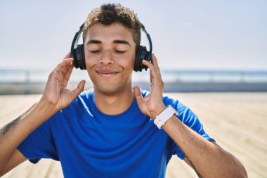 Genç İspanyol adam dışarıda müzik dinleyip kulaklık takıyor.