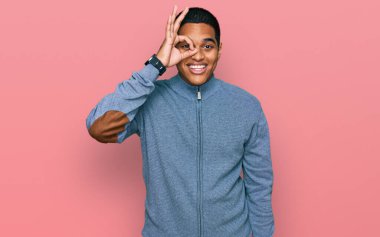 Genç, yakışıklı, sıradan bir tişört giyen, el hareketleriyle gülümseyen, mutlu yüzüyle parmaklarının arasından bakan Latin asıllı bir adam.. 