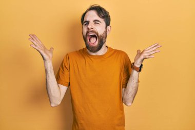 Sıradan sarı tişörtlü beyaz bir adam kolları havada ve gözleri kapalı heyecanlı bir şekilde çılgın ve çılgın bir başarıyı kutluyor. Kazanan konsept 