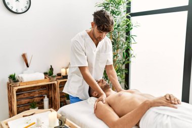 İki İspanyol erkek terapist ve hasta güzellik merkezinde yüz masajı yapıyorlar.