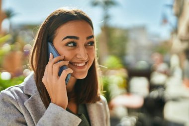 Genç İspanyol kız gülümsüyor. Şehirdeki akıllı telefondan konuşuyor..