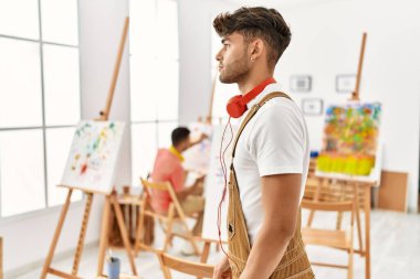 Sanat stüdyosundaki genç İspanyol bir adam profilini rahatlatmak için kendine güvenen bir gülümsemeyle doğal bir poz veriyor.. 