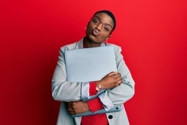 Genç Afro-Amerikalı iş kadını dizüstü bilgisayarını tutuyor ve kameraya bakıyor. Öpücük yolluyor, sevimli ve seksi. aşk ifadesi. 