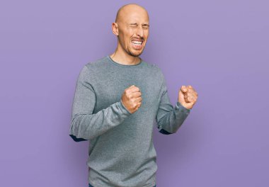 Kel, sakallı, sıradan kıyafetler giyen, başarı için heyecanlanan, kolları havada, gözleri kapalı, zaferi kutlayan, gülümseyen bir adam. Kazanan konsept. 