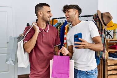 İki İspanyol müşteri alışveriş torbaları tutuyor ve giyim mağazasında akıllı telefon kullanıyor..