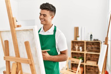 Genç İspanyol adam resim stüdyosunda kendine güvenen gülümsüyor.