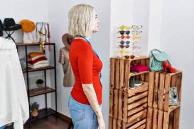 Perakende satış mağazasında yönetici olarak çalışan genç beyaz bir kadın. Taraf arıyor, rahat profil pozu veriyor. Kendine güvenen bir gülümsemesi var.. 