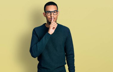 Gündelik kıyafetler ve gözlük takan genç Afro-Amerikalı adam sessiz olmak istiyor. sessizlik ve gizli konsept. 