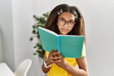Afro-Amerikalı kız evde kitap okuyor.